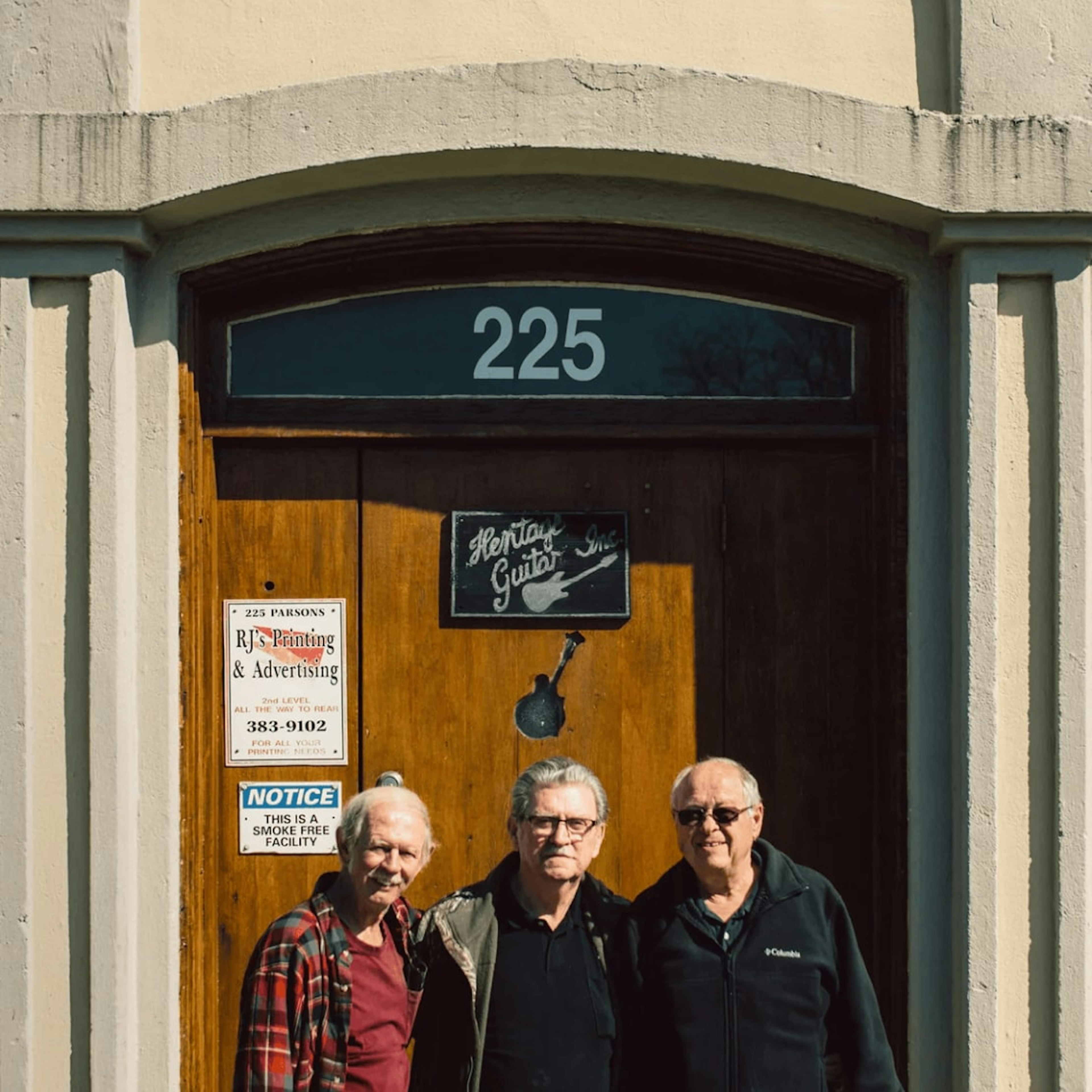 Founders of Heritage Guitar Inc. standing in front of the iconic 225 Parsons Street location, birthplace of legendary craftsmanship in Kalamazoo, Michigan.